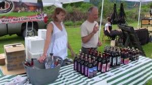 a man and woman telling people about their wine and mead at a festival